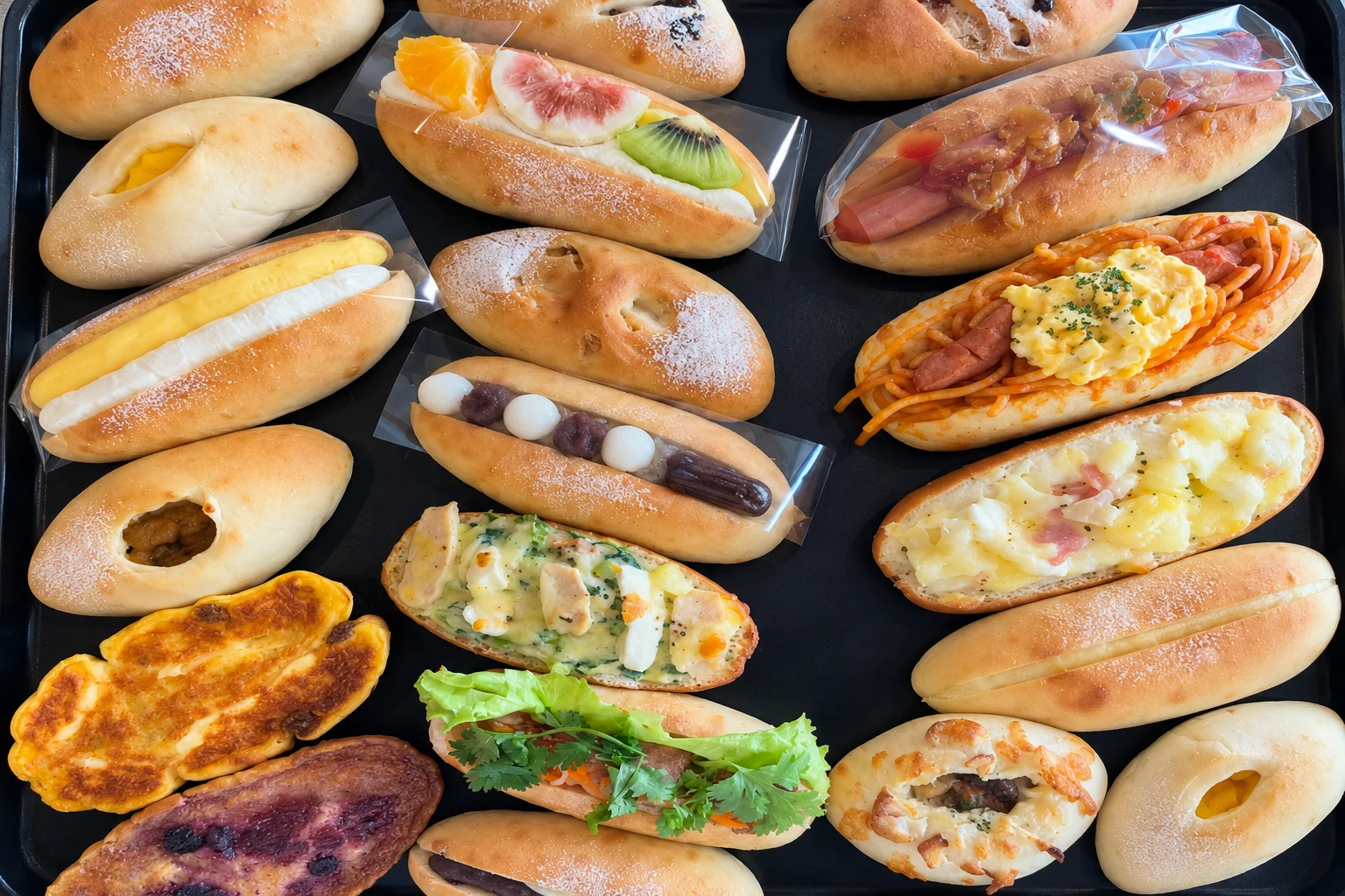 黒い天板に並ぶ、果物やたまごや野菜を挟んだパン